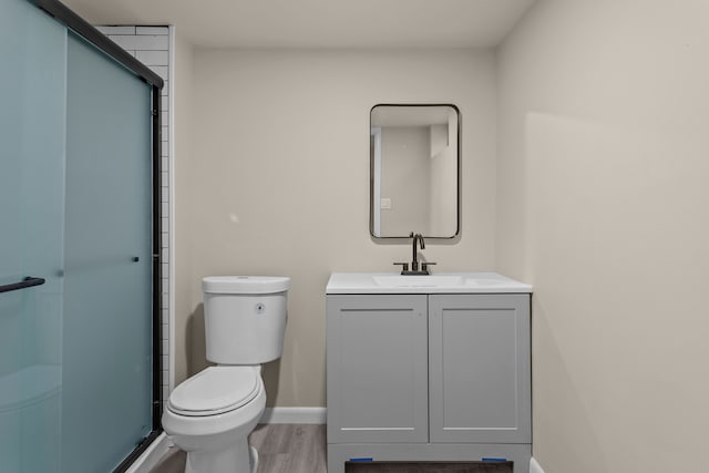 bathroom featuring wood-type flooring, toilet, walk in shower, and vanity