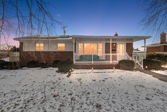 snow covered house featuring covered porch