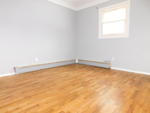 empty room featuring a baseboard radiator and light wood-type flooring