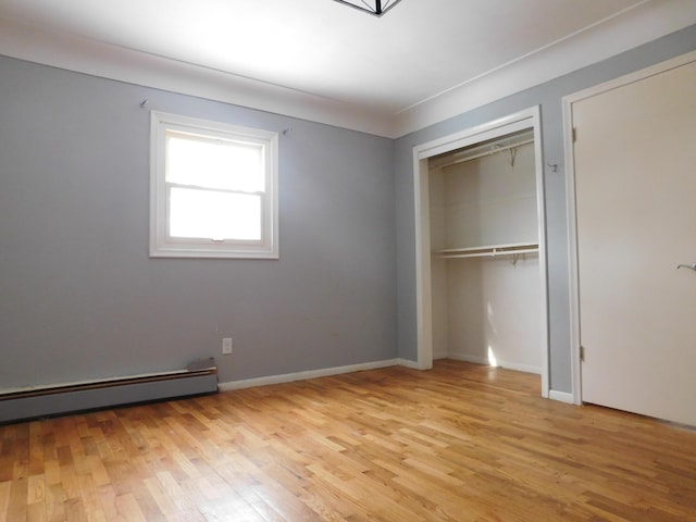 unfurnished bedroom featuring a baseboard heating unit, light hardwood / wood-style flooring, and a closet