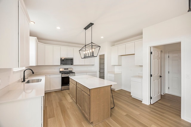 kitchen featuring a center island, white cabinetry, stainless steel gas range, hanging light fixtures, and sink