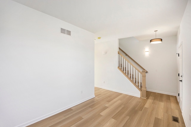 11964 Timber Ct, Bruce, MI 48065 - spare room with baseboards, visible vents, light wood-style flooring, and stairway