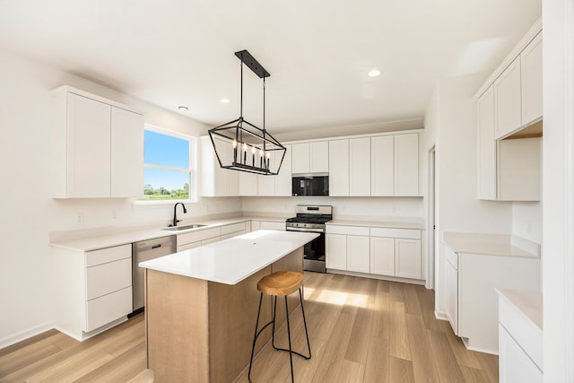 11964 Timber Ct, Bruce, MI 48065 - kitchen featuring appliances with stainless steel finishes, a sink, light wood finished floors, white cabinetry, and a kitchen island