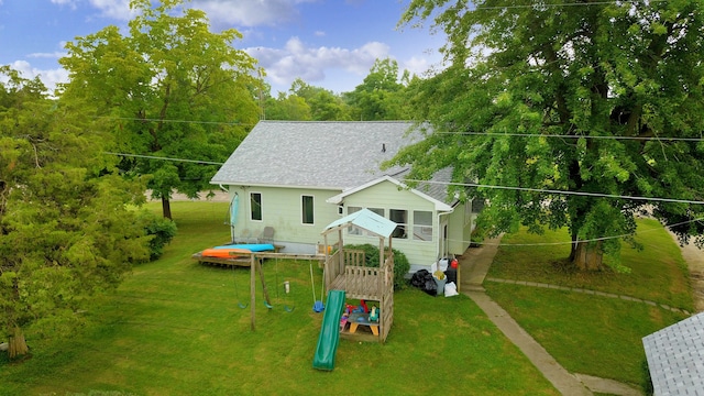 back of property with a lawn and a playground