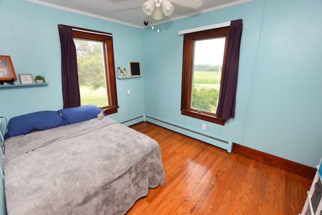 bedroom featuring ceiling fan, a baseboard radiator, multiple windows, and crown molding