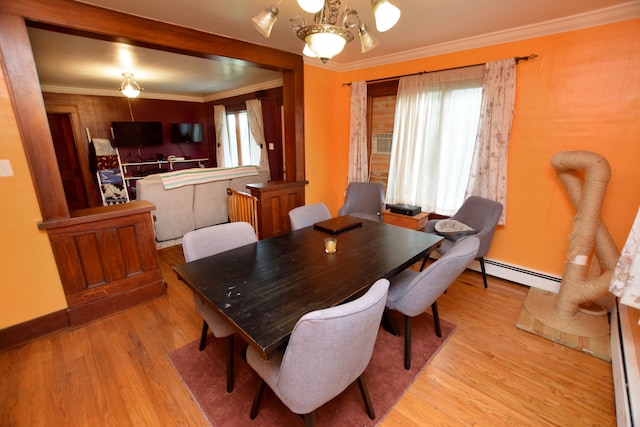 dining room with light wood-type flooring, a baseboard heating unit, an inviting chandelier, and crown molding