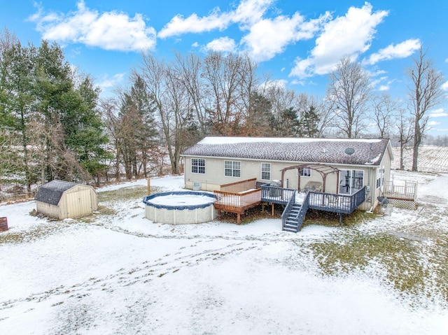 snow covered house with a shed and a swimming pool side deck