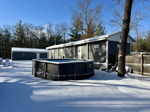 snow covered house featuring a fenced in pool