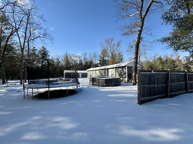 snowy yard featuring a pool and a trampoline