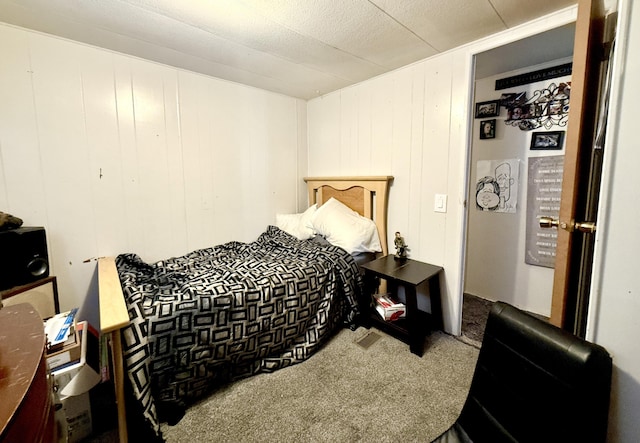 carpeted bedroom featuring wooden walls