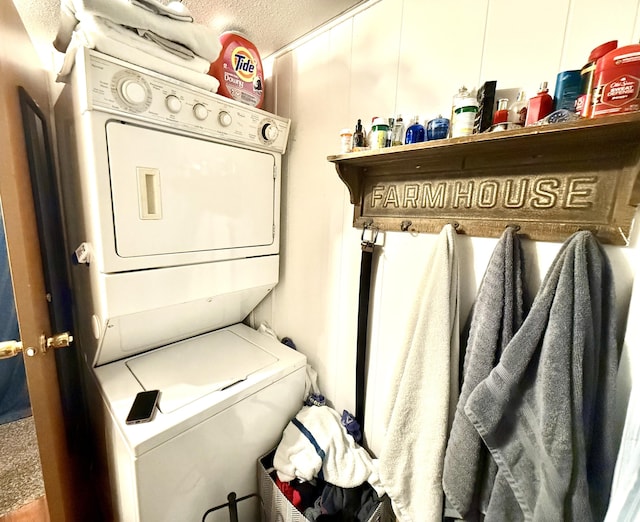 clothes washing area featuring a textured ceiling and stacked washer and clothes dryer