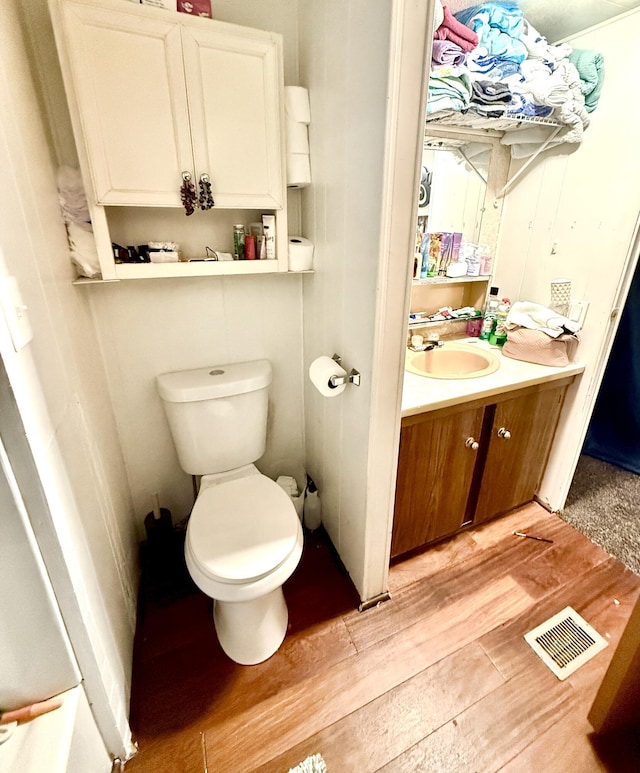 bathroom with hardwood / wood-style floors, toilet, and vanity