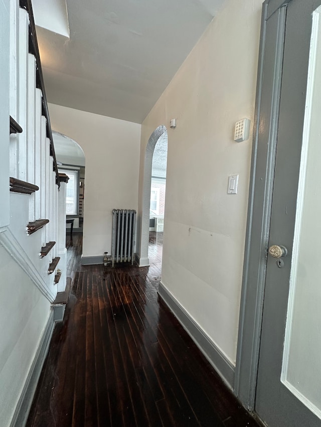 hallway featuring dark wood-type flooring and radiator heating unit