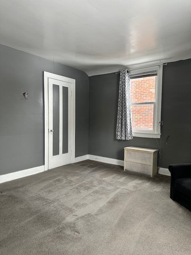 spare room featuring carpet flooring and radiator