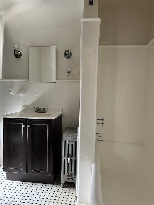 bathroom featuring tile walls, vanity, shower / washtub combination, radiator, and decorative backsplash