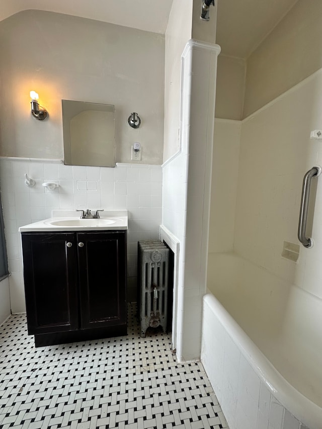 bathroom featuring vanity, radiator heating unit, tub / shower combination, and tile walls