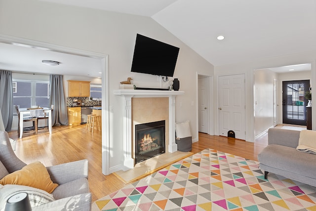 living room featuring a fireplace, light hardwood / wood-style flooring, a healthy amount of sunlight, and vaulted ceiling