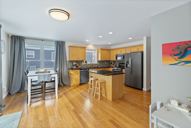 kitchen with tasteful backsplash, a breakfast bar, a kitchen island, light hardwood / wood-style floors, and stainless steel appliances