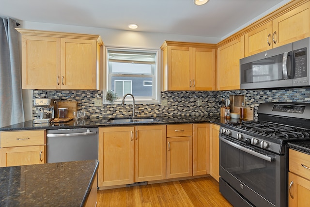 kitchen featuring sink, dark stone counters, appliances with stainless steel finishes, and backsplash