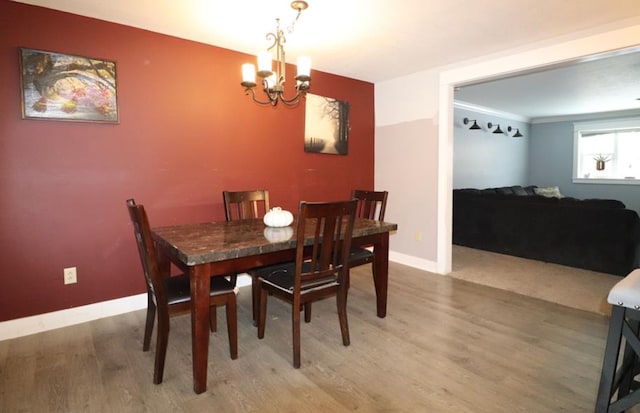 dining room with hardwood / wood-style flooring, ornamental molding, and an inviting chandelier