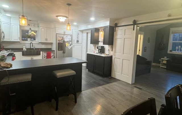 kitchen featuring decorative light fixtures, sink, white cabinets, stainless steel fridge with ice dispenser, and a barn door