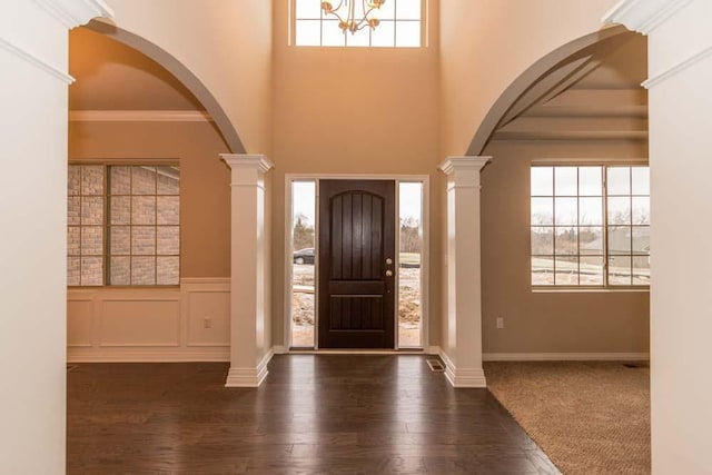 foyer entrance with crown molding, dark wood-type flooring, and ornate columns