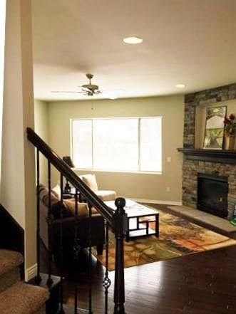 interior space featuring ceiling fan, a stone fireplace, and hardwood / wood-style floors