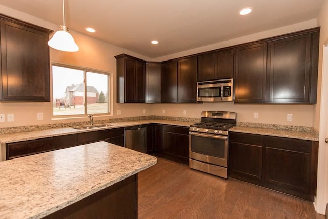 kitchen featuring appliances with stainless steel finishes, hanging light fixtures, sink, dark brown cabinetry, and dark hardwood / wood-style floors