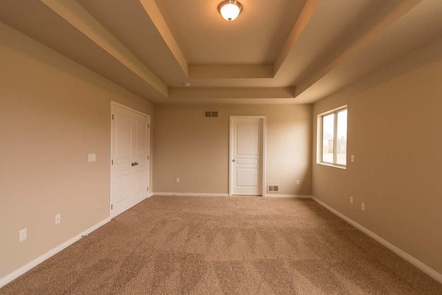 carpeted spare room featuring a tray ceiling