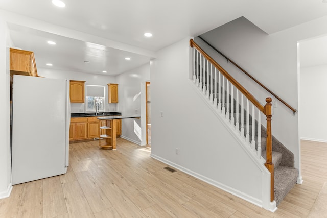 kitchen with sink, light hardwood / wood-style flooring, and white refrigerator