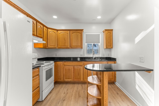 kitchen featuring sink, white appliances, a kitchen bar, and light hardwood / wood-style flooring