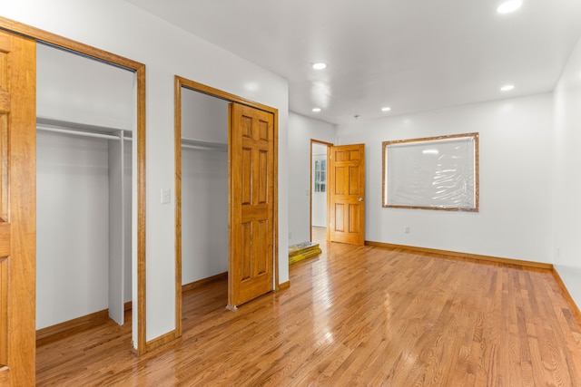 unfurnished bedroom featuring light wood-type flooring and two closets