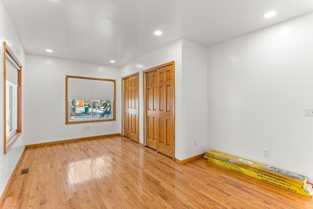 unfurnished bedroom with multiple closets and light wood-type flooring