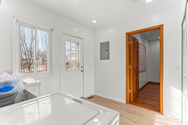 interior space featuring washing machine and dryer, light hardwood / wood-style flooring, and electric panel