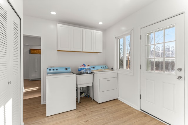 washroom with cabinets, light wood-type flooring, and separate washer and dryer