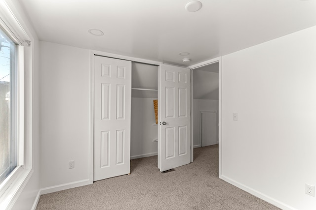 unfurnished bedroom with a closet and light colored carpet