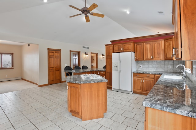 kitchen with white fridge with ice dispenser, a center island, sink, backsplash, and vaulted ceiling