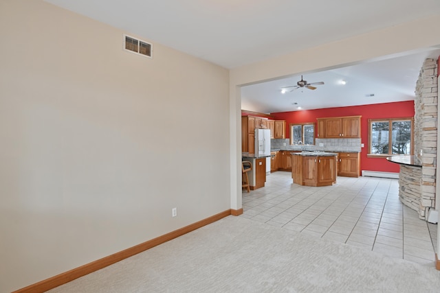 kitchen with a kitchen island, a baseboard heating unit, tasteful backsplash, ceiling fan, and light tile patterned floors