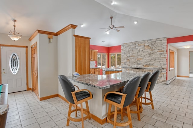 kitchen with light tile patterned floors, stone counters, kitchen peninsula, and lofted ceiling