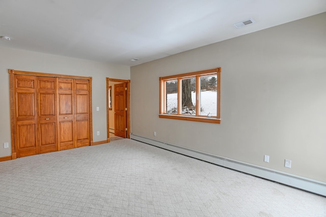 unfurnished bedroom with carpet, a closet, and a baseboard heating unit