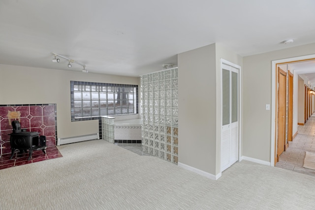 interior space featuring a wood stove, rail lighting, and a baseboard radiator