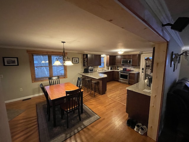 dining area featuring sink, light hardwood / wood-style flooring, ornamental molding, and an inviting chandelier