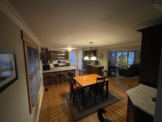 dining area featuring wood-type flooring, a chandelier, and ornamental molding