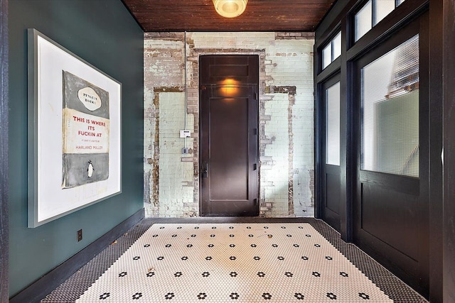 tiled entrance foyer featuring brick wall and wooden ceiling