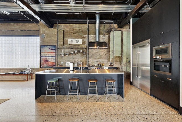 kitchen with built in appliances, sink, and a breakfast bar area