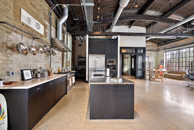 kitchen featuring sink, beam ceiling, high vaulted ceiling, built in appliances, and an island with sink