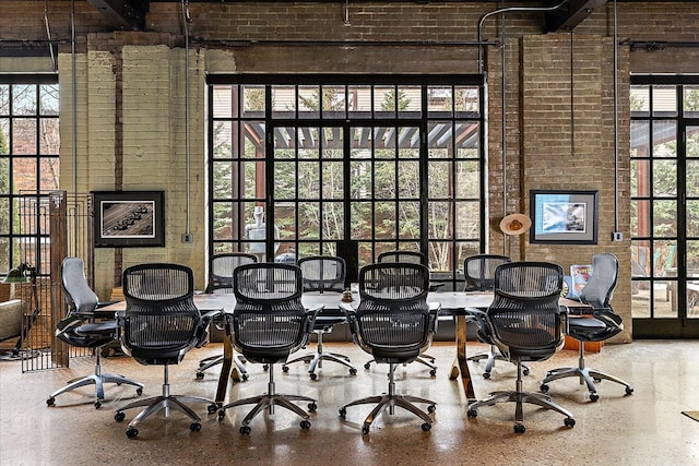 interior space featuring beamed ceiling, brick wall, plenty of natural light, and a towering ceiling