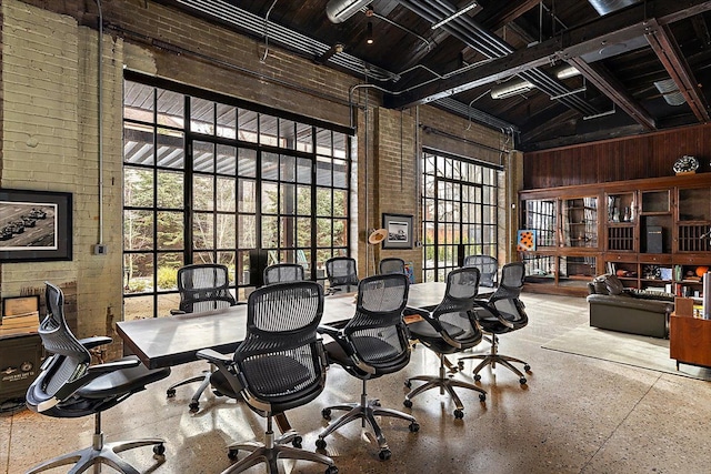 office space with brick wall, plenty of natural light, and high vaulted ceiling