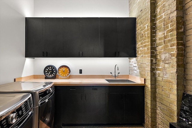 kitchen with brick wall, sink, and washing machine and clothes dryer