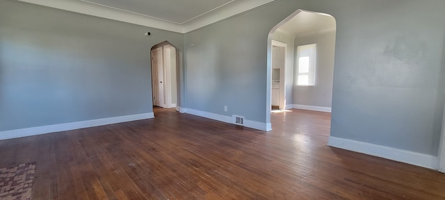 empty room with ornamental molding and dark hardwood / wood-style floors